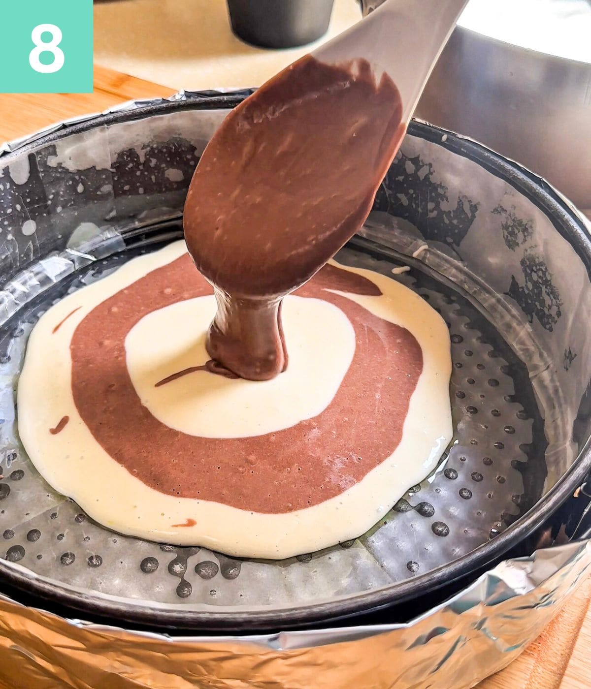 Creating a zebra pattern from the batter by dropping both batters alternatively into the centre of the baking pan.