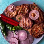 chicken and vegetable kebabs on a plate with sliced onions and chili.