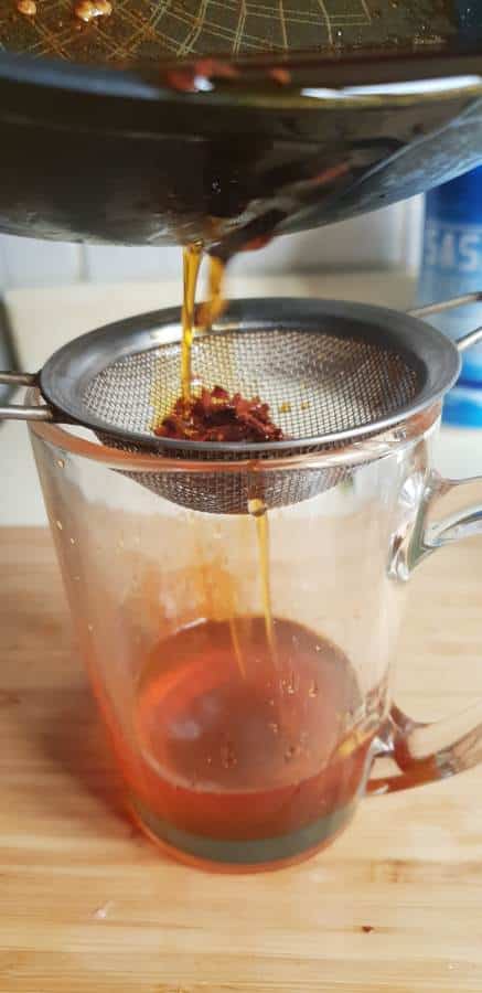 straining chilies in a strainer to get chili oil