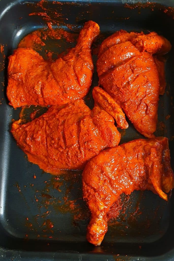 marinated chicken legs and thigh pieces in a baking dish.