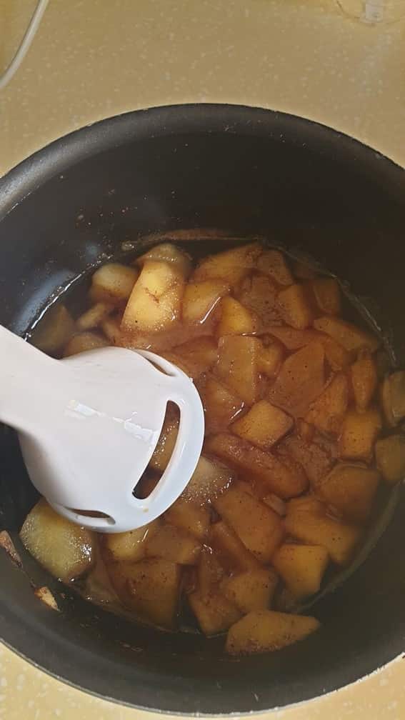 handblending cooked apples in a black sauce pan