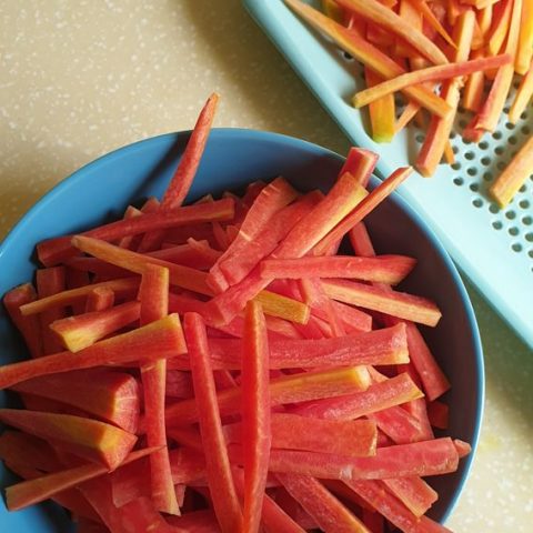 blue bowl full of sliced carrots