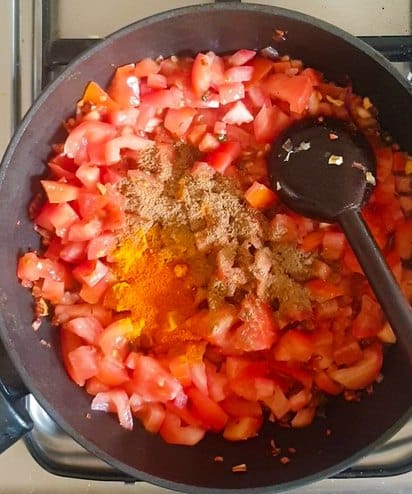 diced tomatoes and spices in a black wok