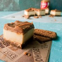 a head on view of the no bake biscoff custard bar with more bars in the background blurred out, against a blue backdrop