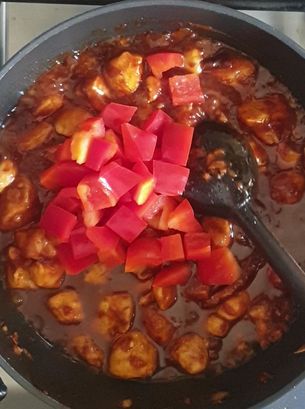 add red bell peppers cubes into chicken schezwan 