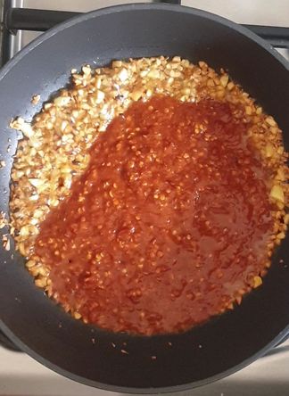 garlic and red chili paste in oil in a black wok