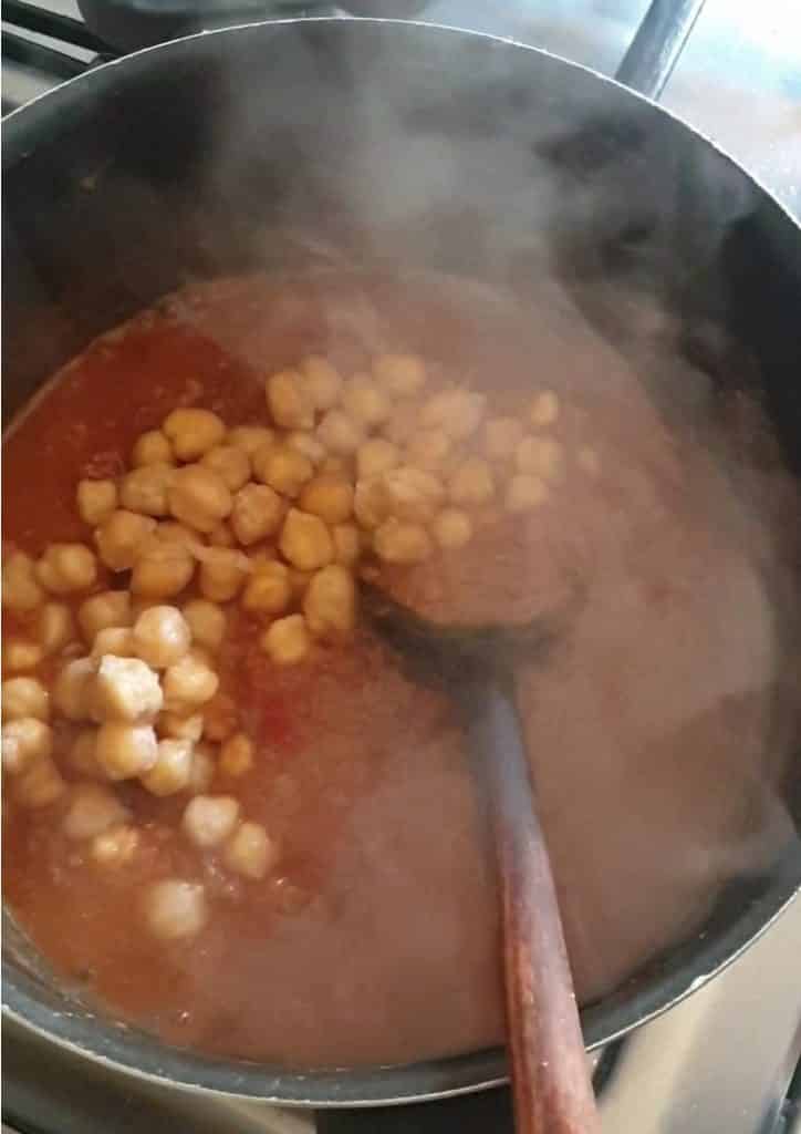 cholay ka salan with boiled chickpeas added to it in a blackpot