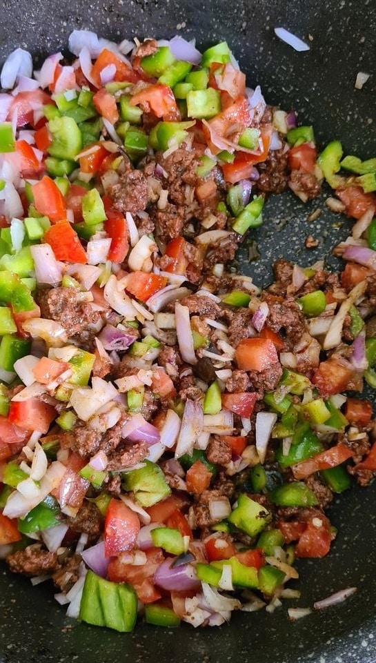 chopped veggie and minced beef stirred in together in a black pan