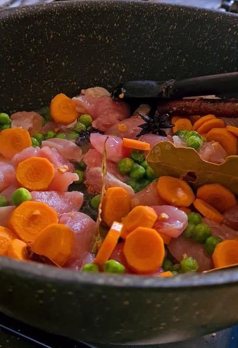 chicken, peas and carrots in a pot