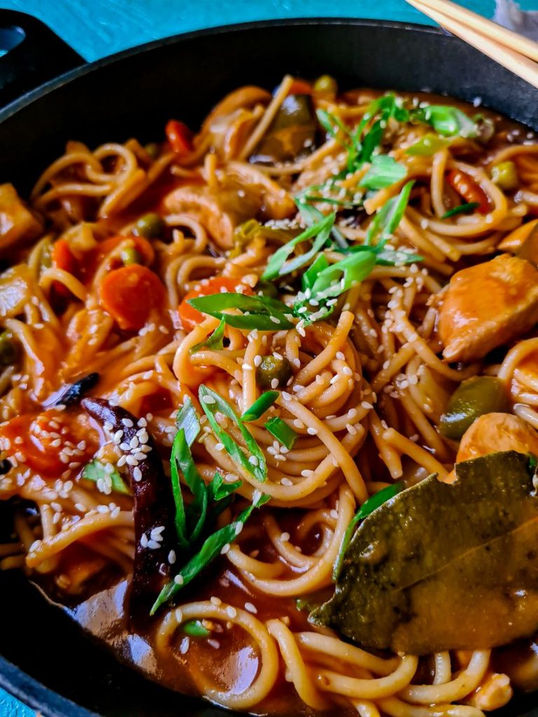 chicken vegetable and noodles in a black wok