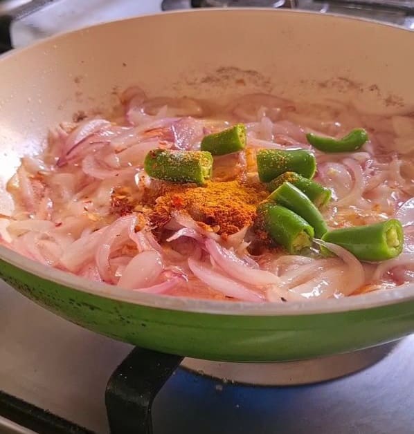 chopped green chilies and spices added to translucent onions in a pan