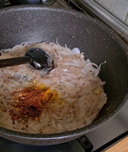 spices added to translucent onion slices in a pan