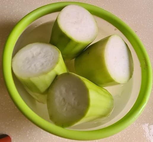 bottle gourd / loki cut into 4 segments and peeled, immersed in a bowl full of water