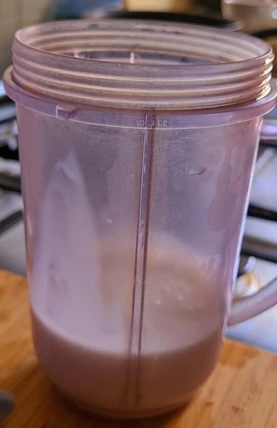 a white thick almond and milk liquid in a small plastic jug