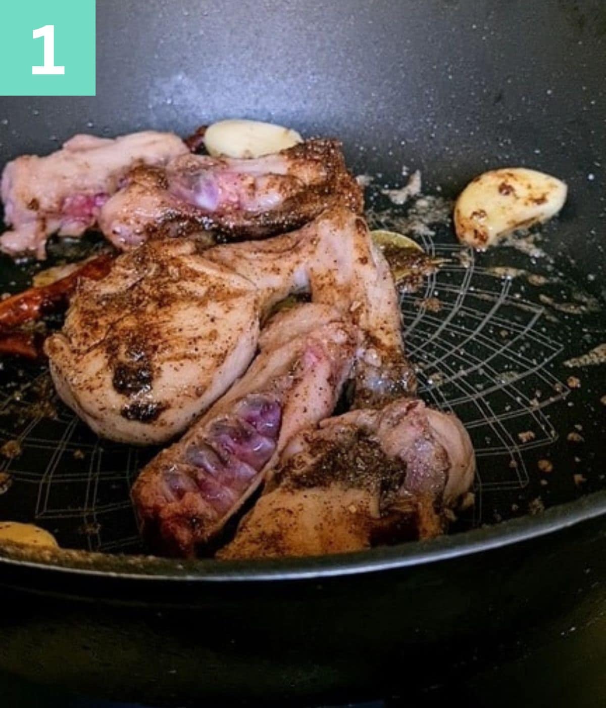 raw chicken pieces and spices in a pan.