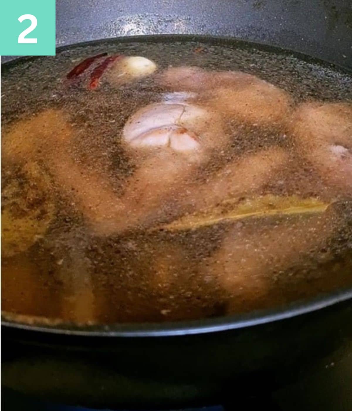 Chicken pieces submerged in spicy water.