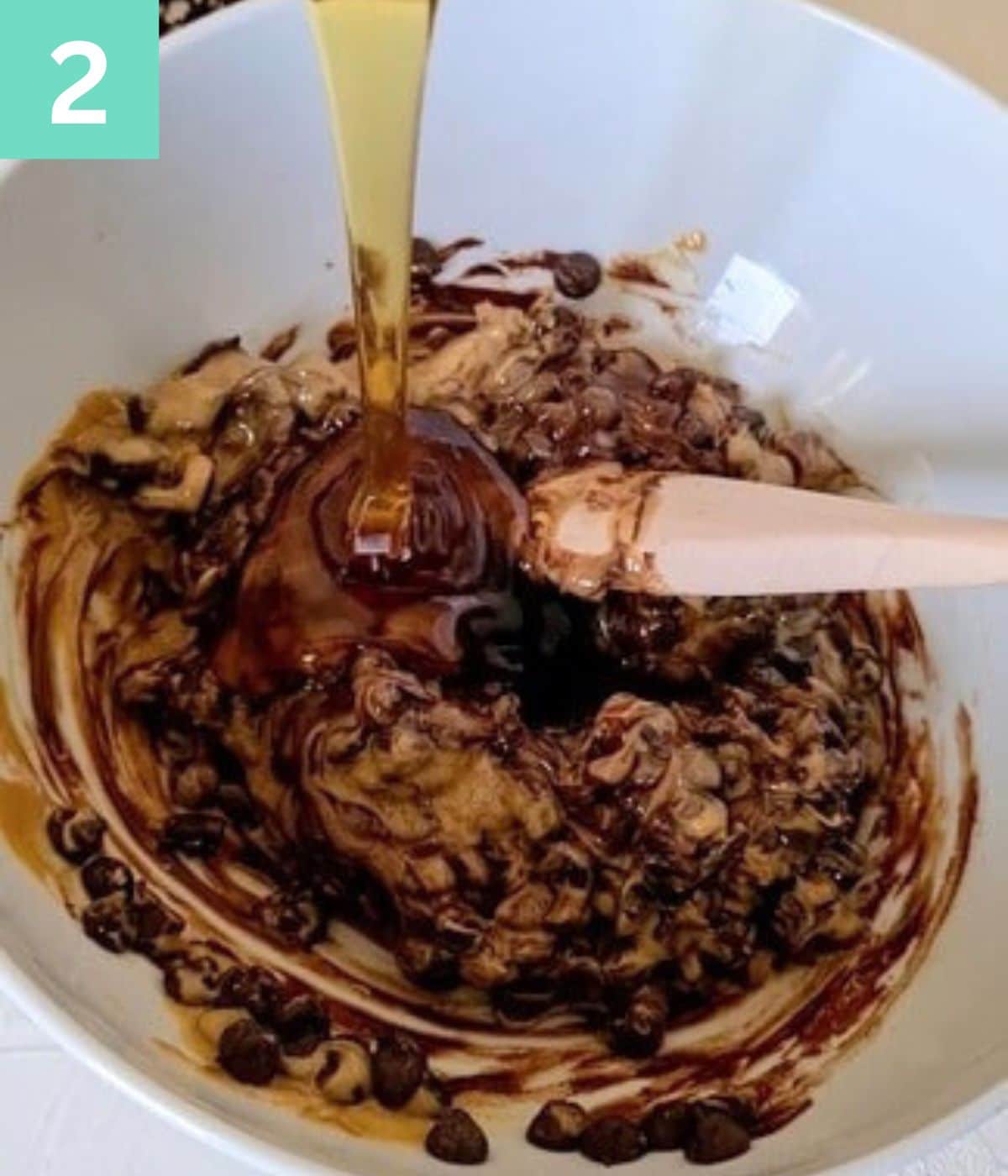 honey added to a bowl of semi-mixed peanutbutter and chocolate chips.