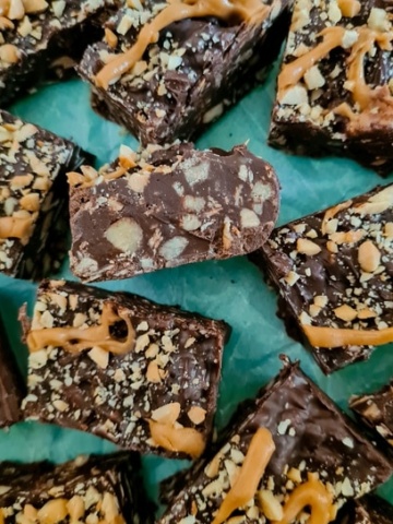 chocolate bars strewn with nuts and oats, sprinkled with some more nuts and peanut butter sauce