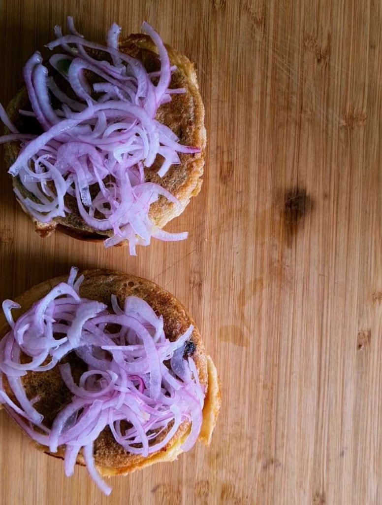 sliced onions on top of the kababs in a bun