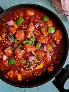 sweet and sour chicken with gravy in a black wok