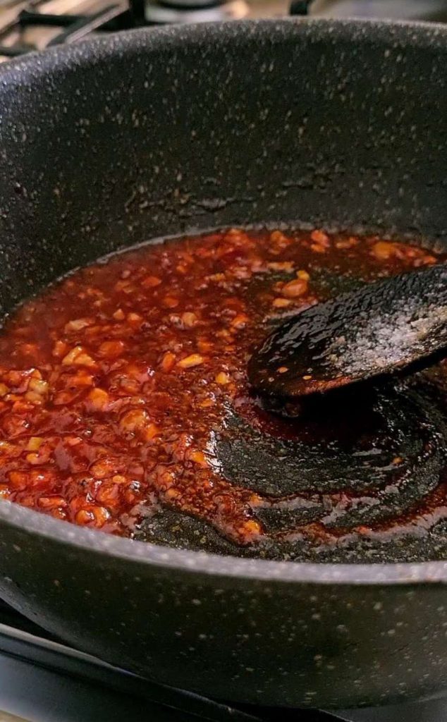 red gravy base being sauteed in a black pan