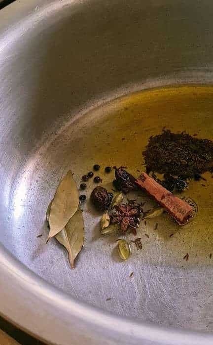 whole spices with oil in a steal pot