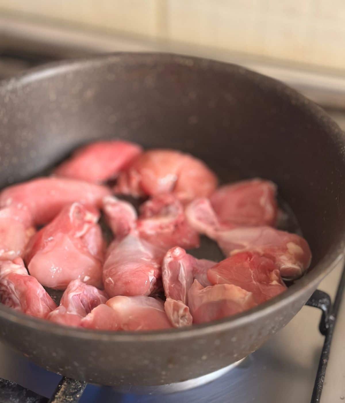 raw chicken in a deep pan with oil