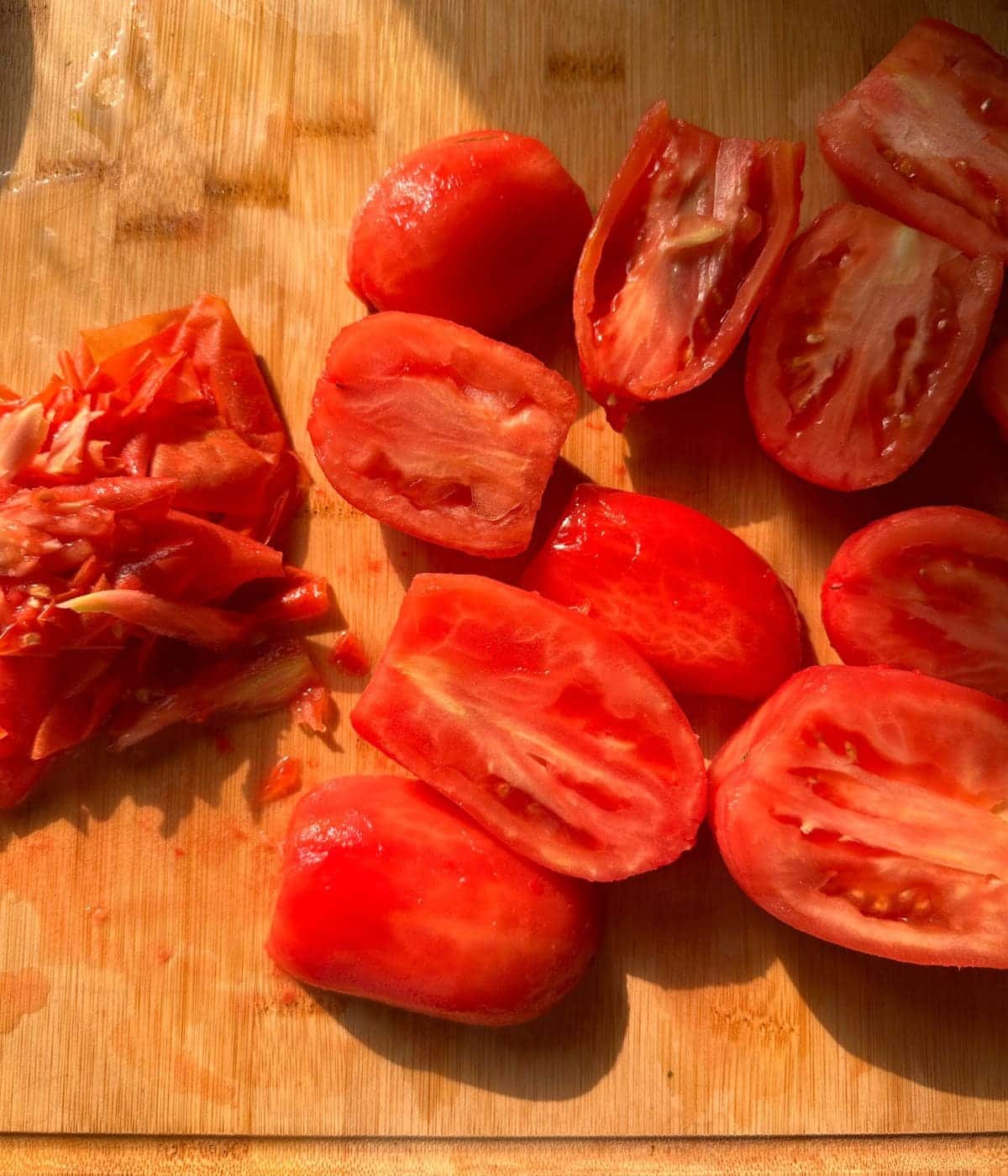 peeled skins of tomatoes piled on the side, and peeled tomatoes kept cut open in halves