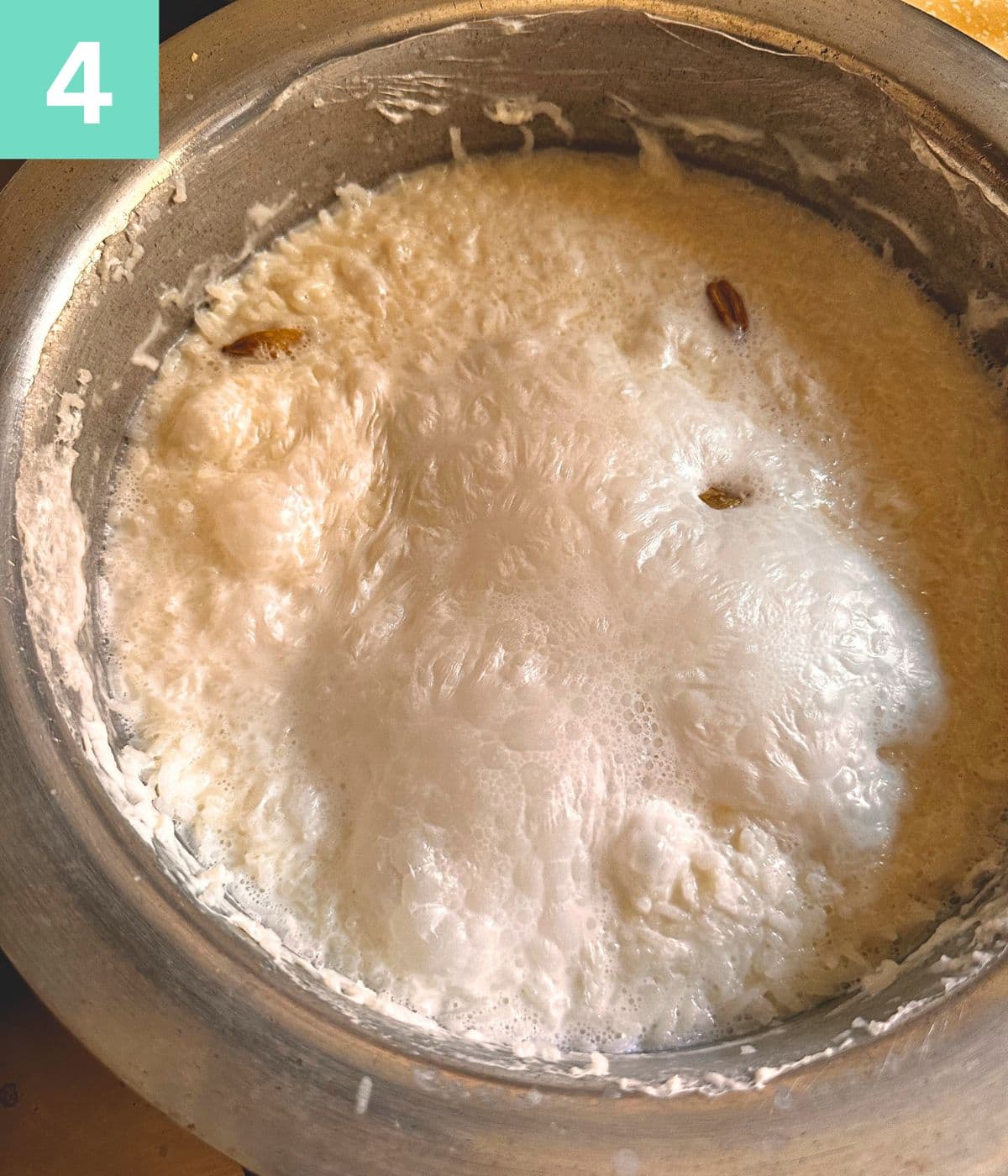milk and rice boiling in a pot forming a crust on top