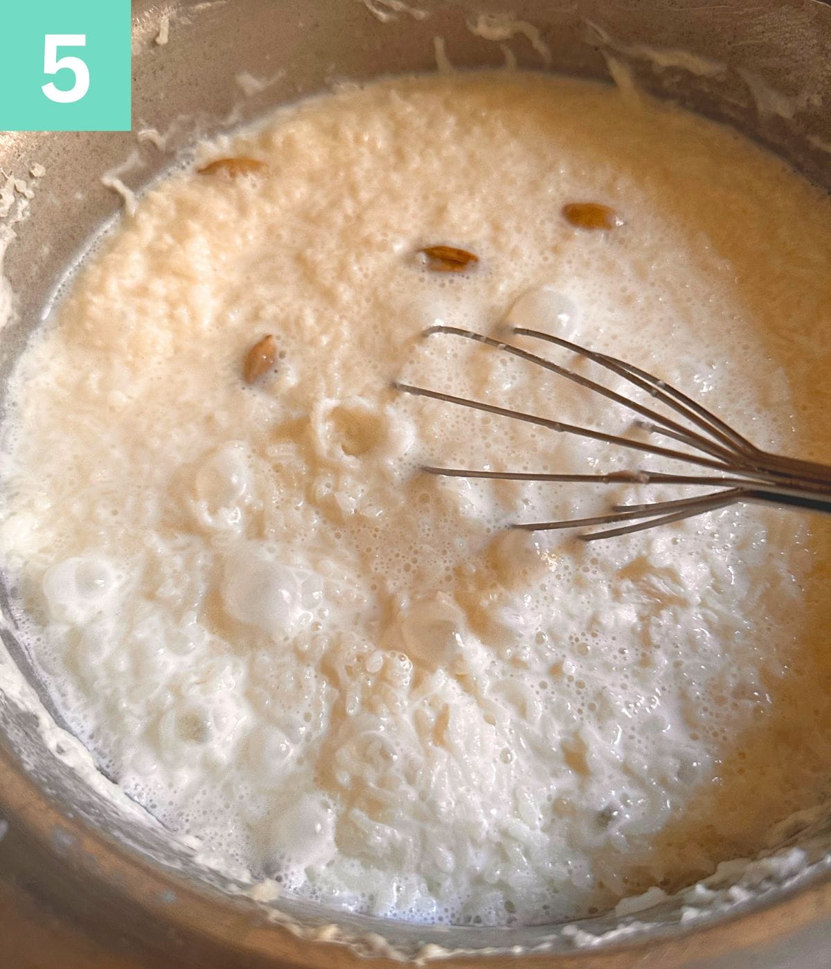 rice and milk cooking, being mixed with a whisk