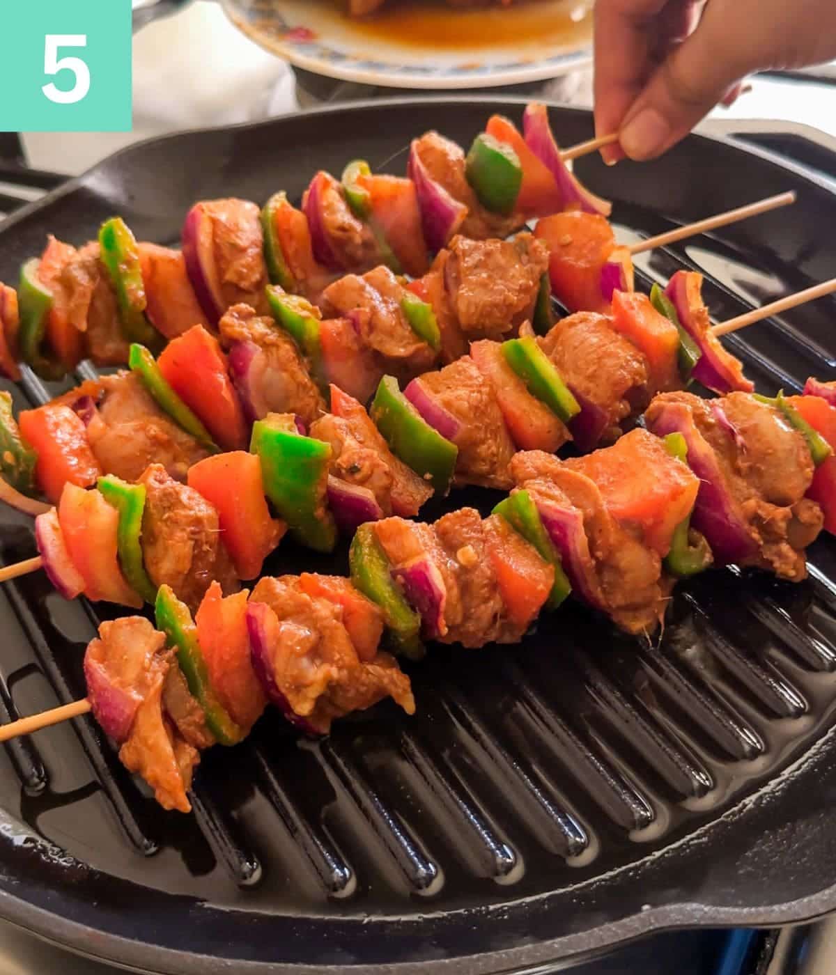 grilling chicken skewers on a grill pan.