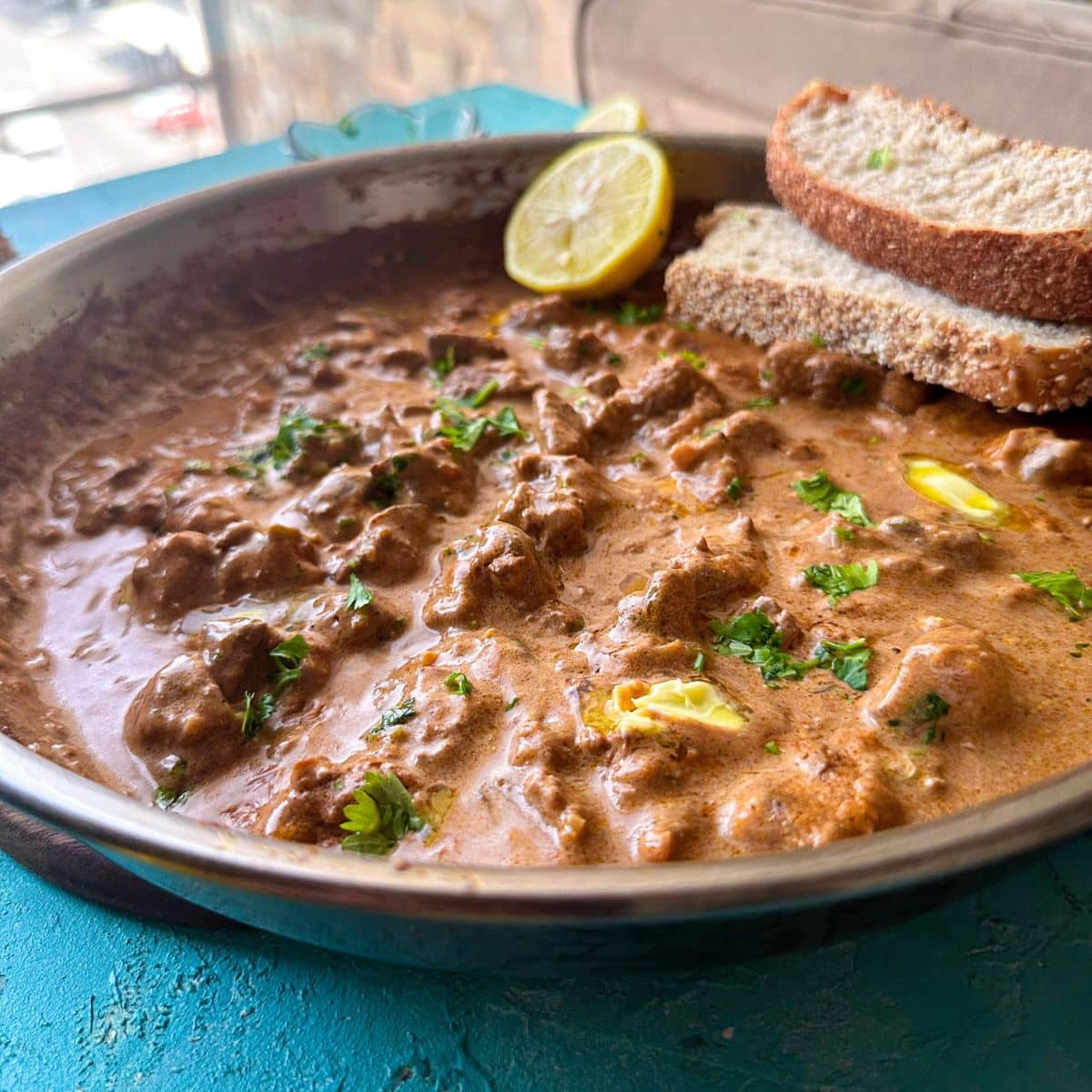 peri peri chicken liver served in a skillet with bread slices and lemon on the side.