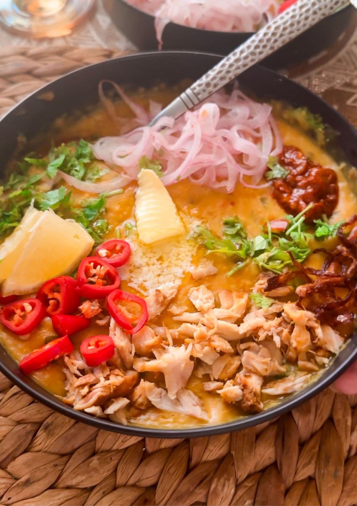 khichdi topped with multiple toppings like cilantro, achaar, onions, red chilies and shredded chicken.