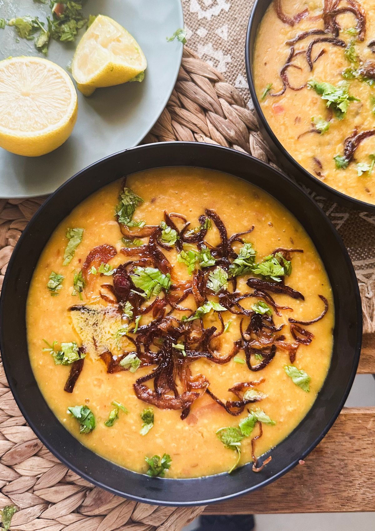spicy oats khichdi served in bowl garnished with cilantro and fried onions.