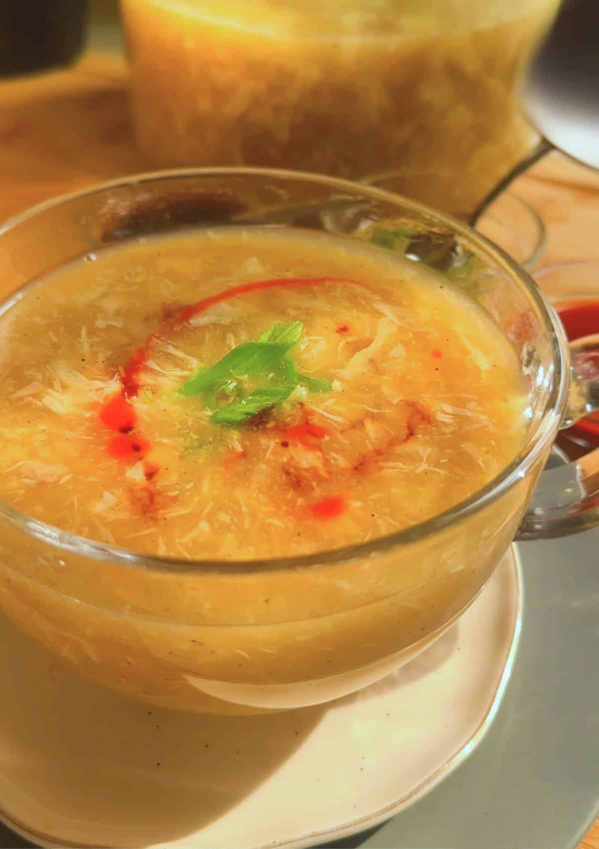 chicken corn soup served in a bowl with toppings.