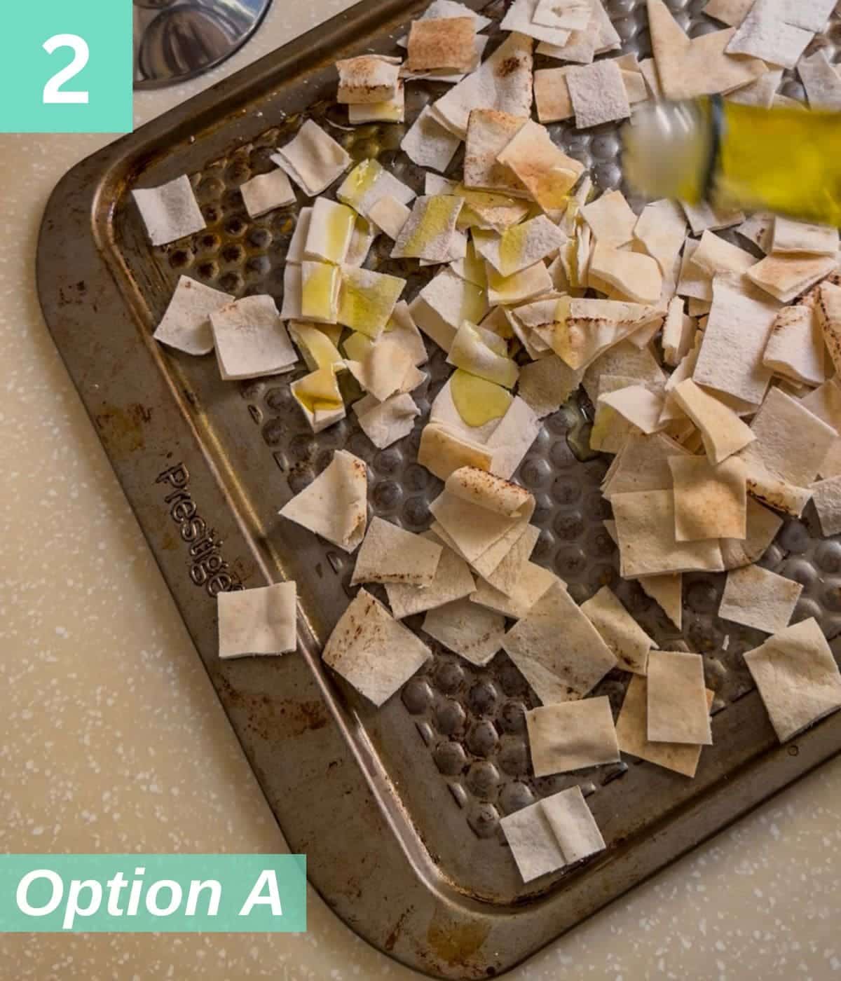 olive oil drizzling on pita chips in a baking tray.